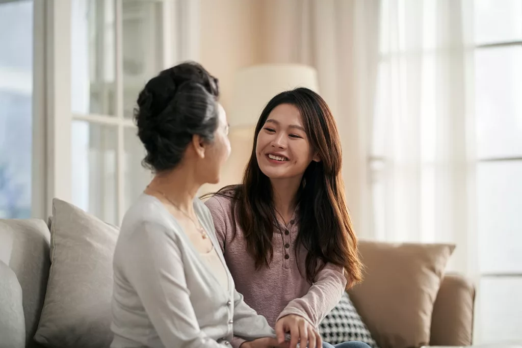 adult daughter and senior mother enjoying a happy conversation at home